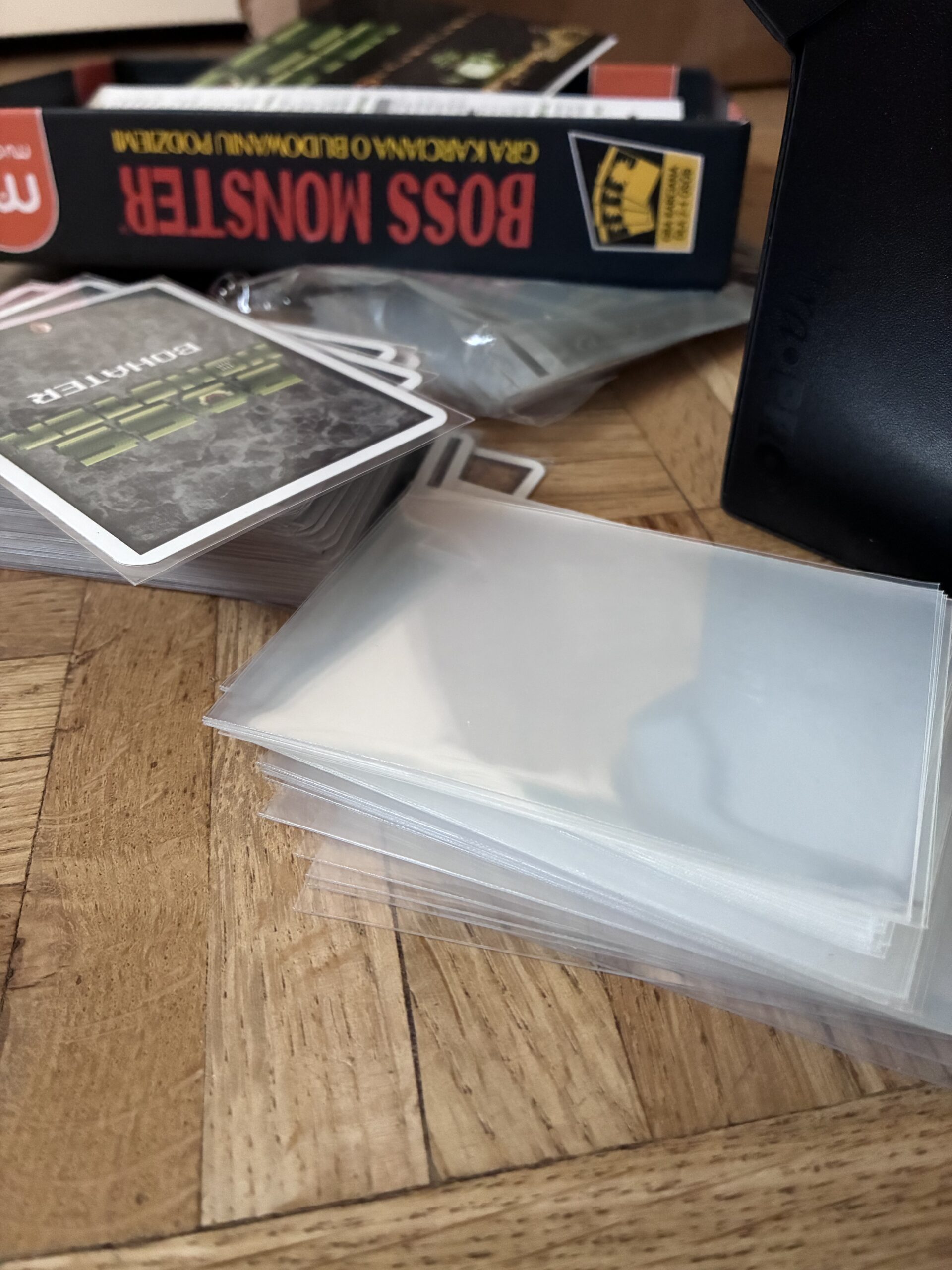 karty, osłonki na karty i pudełko gry boss monster.