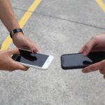 close up of hands holding smartphones outdoors