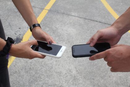 close up of hands holding smartphones outdoors