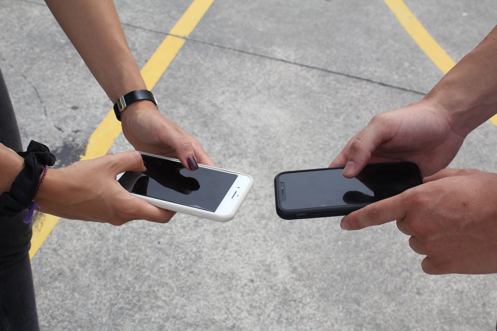 close up of hands holding smartphones outdoors